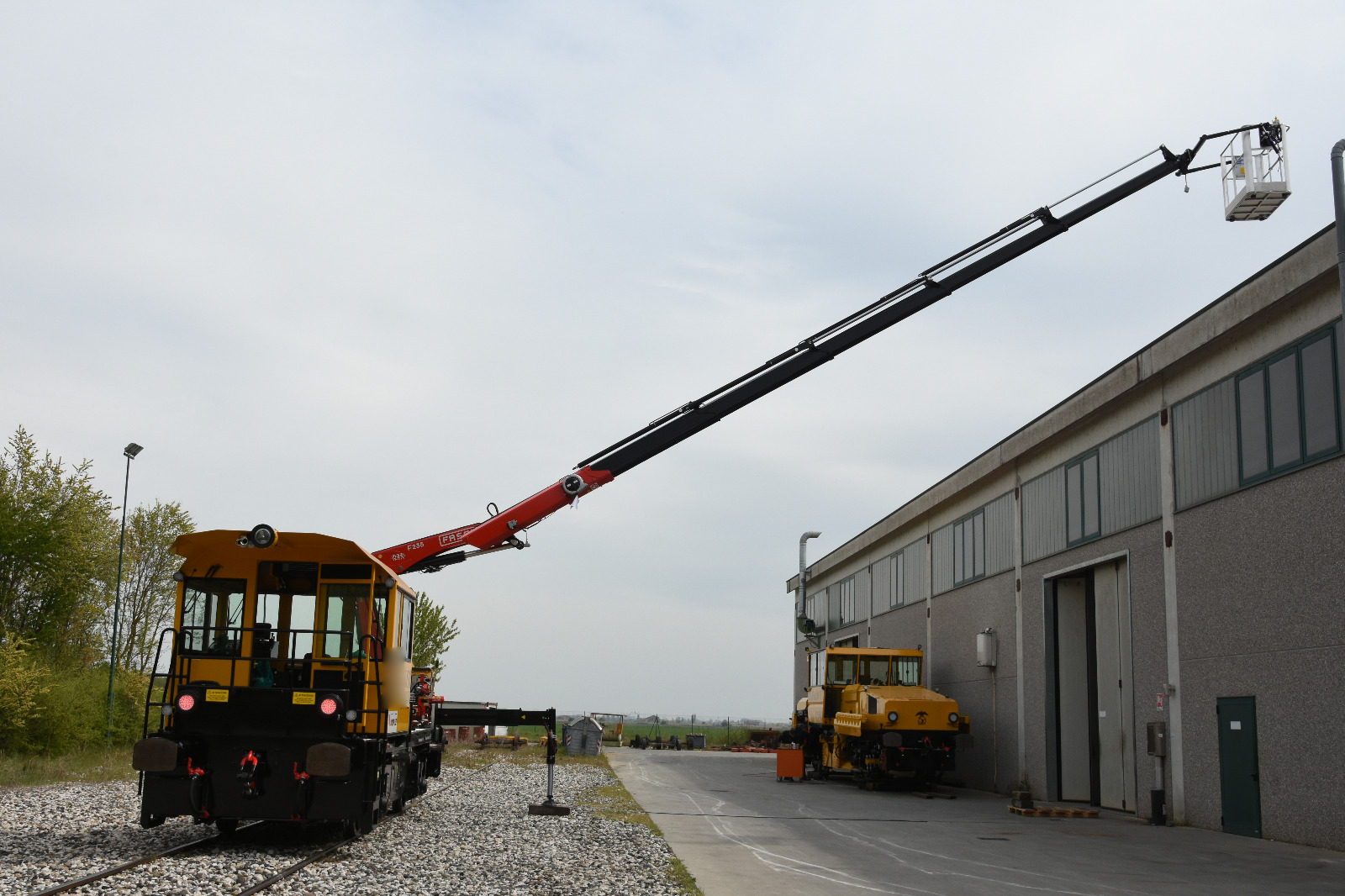 Motocarrello ferroviario con cestello elevabile e braccio esteso su rotaia